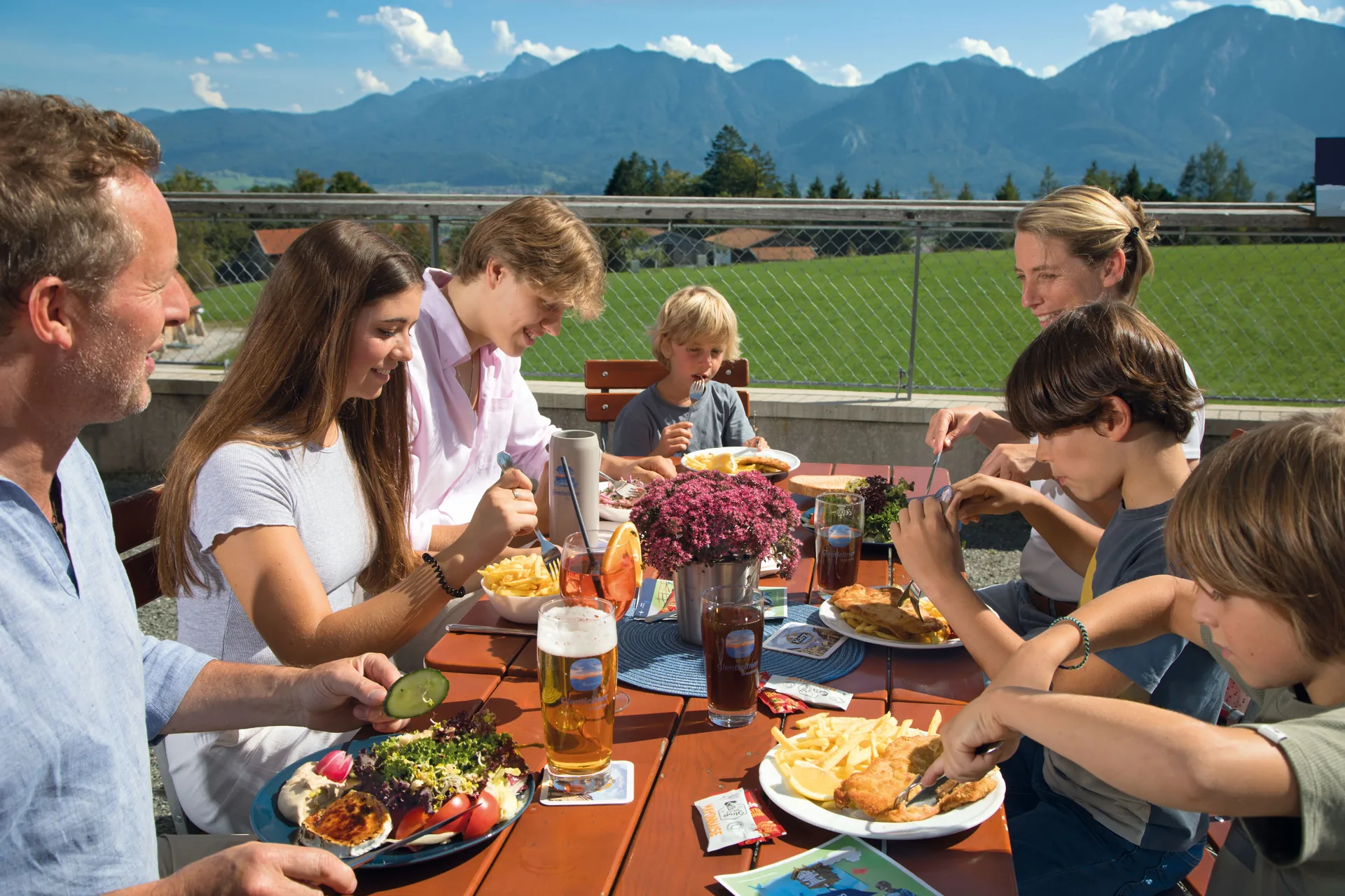 Familie beim gemeinsamen Essen auf der Aussichtsterrasse vor dem Bergpanorama